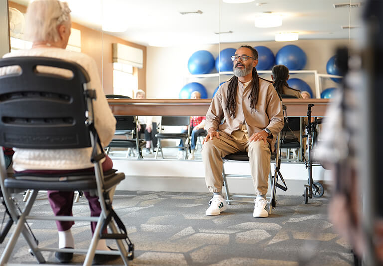 Exercise in community room with chairs and exercise balls.