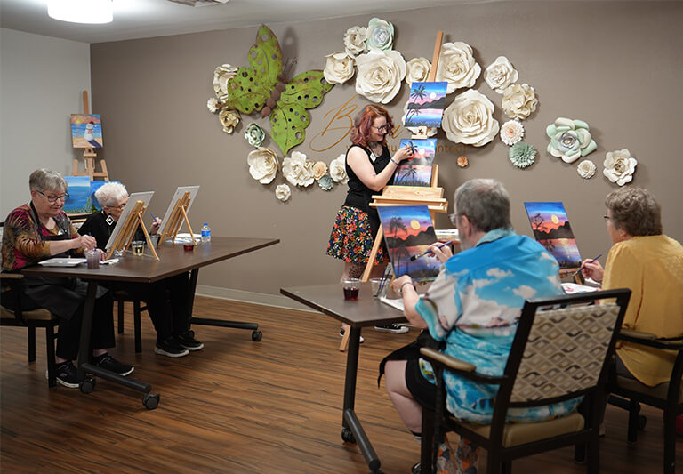 Senior residents enjoy a painting in a creatively decorated room.
