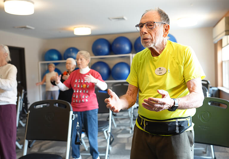 Residents engaging in a group exercise in a bright fitness room with exercise balls.